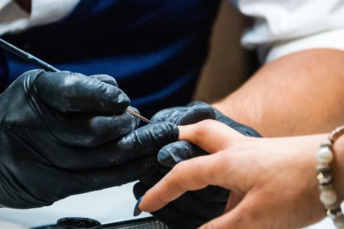 Professionnelle gantée réalisant une manucure dans un salon de beauté